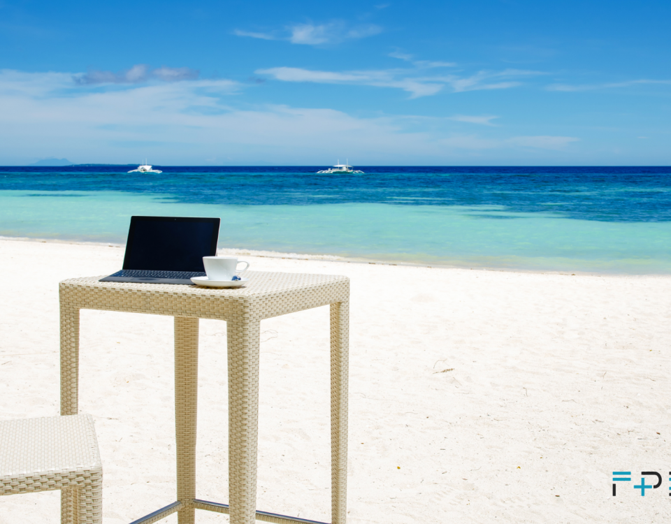 aptop i filiżanka kawy na plaży – symbol powrotu z wakacji do pracy biurowej.